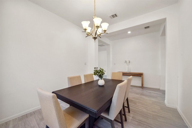 dining space featuring light hardwood / wood-style floors and an inviting chandelier