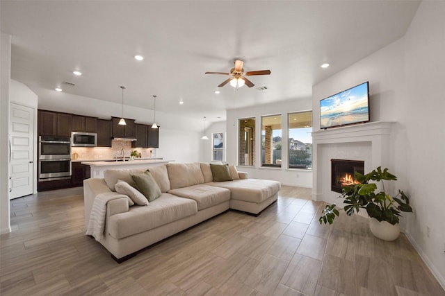 living room with ceiling fan, light hardwood / wood-style flooring, and sink