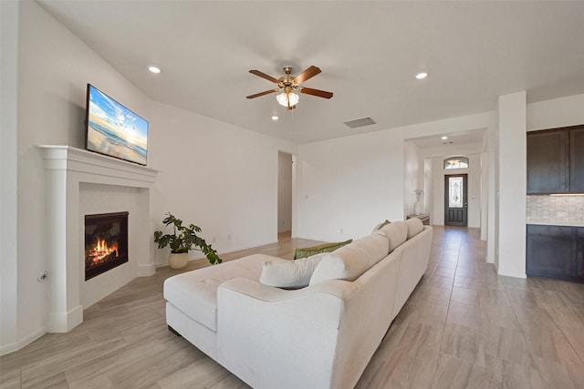 living room with ceiling fan and light hardwood / wood-style flooring