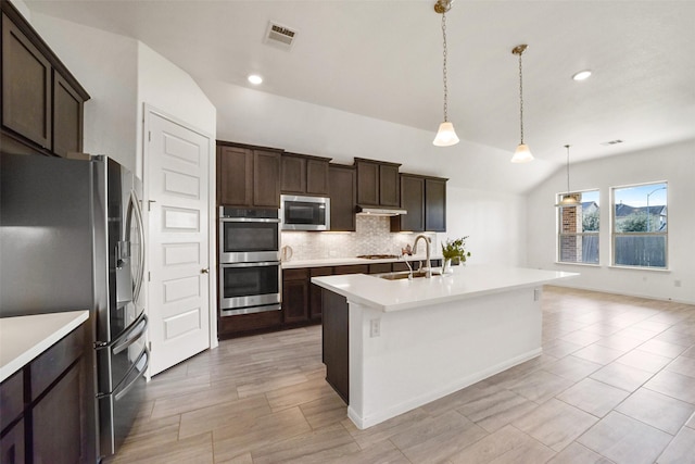 kitchen with sink, pendant lighting, lofted ceiling, a kitchen island with sink, and appliances with stainless steel finishes