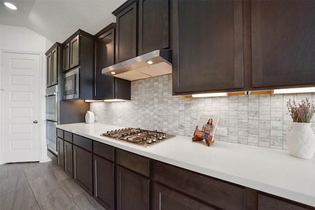 kitchen featuring backsplash, dark brown cabinetry, stainless steel appliances, and vaulted ceiling