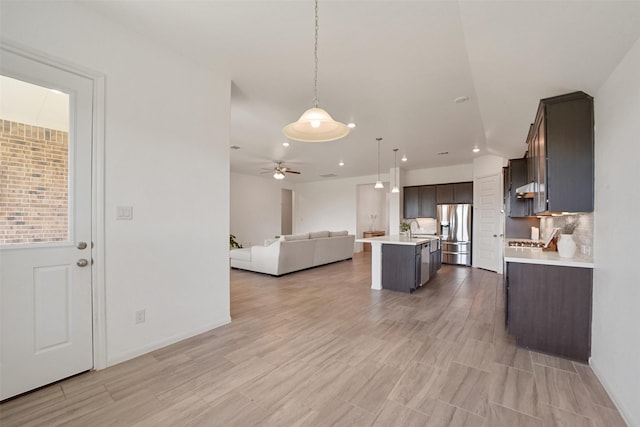 kitchen featuring stainless steel fridge with ice dispenser, a center island with sink, decorative light fixtures, and dark brown cabinets