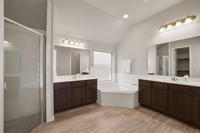 bathroom featuring vanity, independent shower and bath, and lofted ceiling