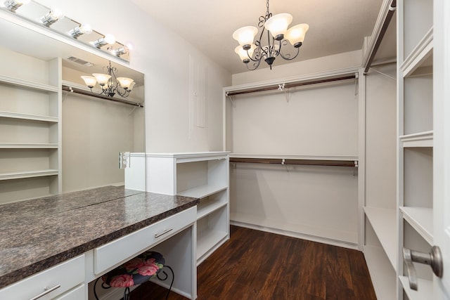 walk in closet featuring dark wood-type flooring and an inviting chandelier