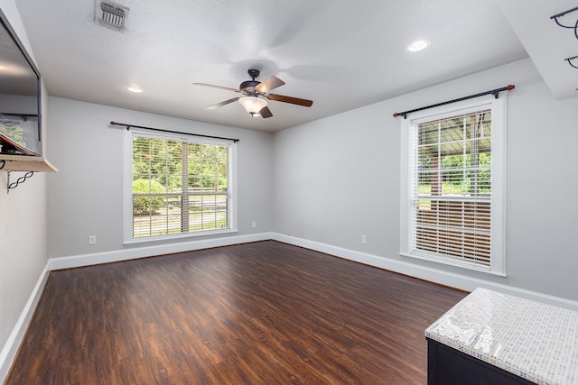 spare room with a wealth of natural light, dark wood-type flooring, and ceiling fan