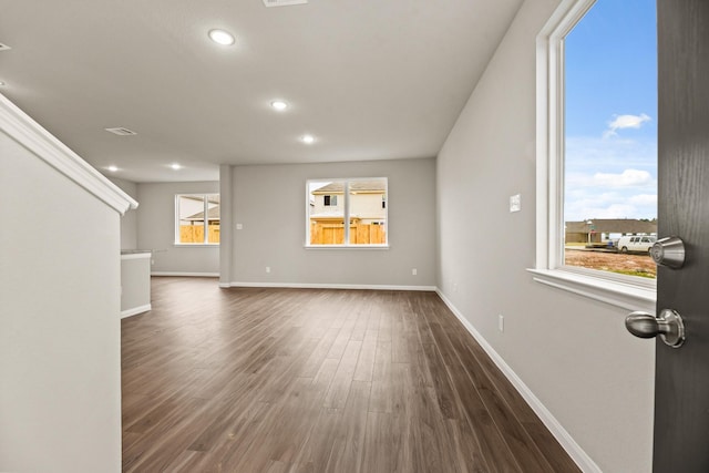 unfurnished living room featuring a healthy amount of sunlight and dark wood-type flooring