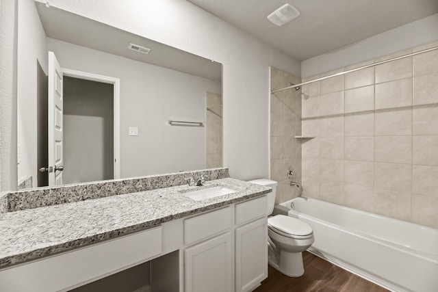 full bathroom featuring vanity, hardwood / wood-style flooring, toilet, and tiled shower / bath