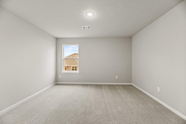 carpeted empty room featuring a textured ceiling