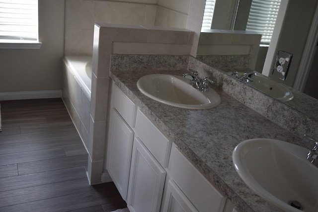 bathroom with hardwood / wood-style flooring, vanity, and a washtub