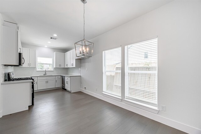8211 Gladstone St, Houston, TX 77051 - kitchen with stainless steel appliances, a chandelier, backsplash, dark wood-style floors, and white cabinetry