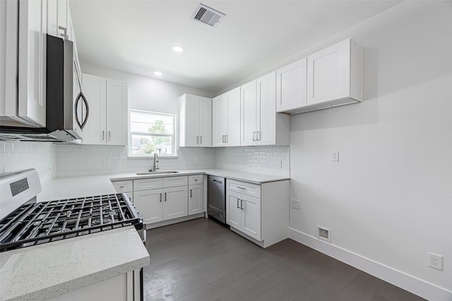 kitchen featuring white cabinetry, sink, dark hardwood / wood-style flooring, decorative backsplash, and appliances with stainless steel finishes