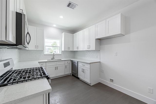 8211 Gladstone St, Houston, TX 77051 - kitchen with appliances with stainless steel finishes, light stone counters, decorative backsplash, dark wood-style flooring, and white cabinetry