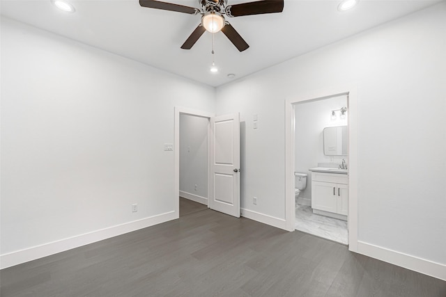 unfurnished bedroom featuring dark hardwood / wood-style flooring, ensuite bathroom, ceiling fan, and sink