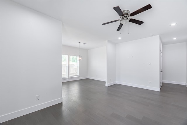 empty room with dark wood-type flooring and ceiling fan with notable chandelier