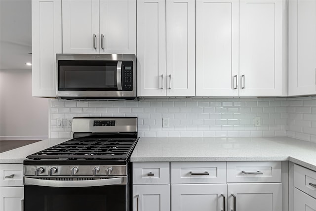 kitchen featuring tasteful backsplash, light stone countertops, white cabinets, and stainless steel appliances