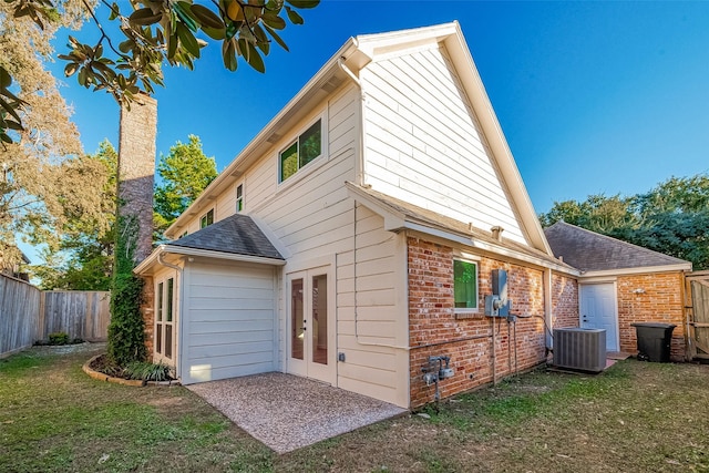 rear view of house with a lawn, central air condition unit, and french doors