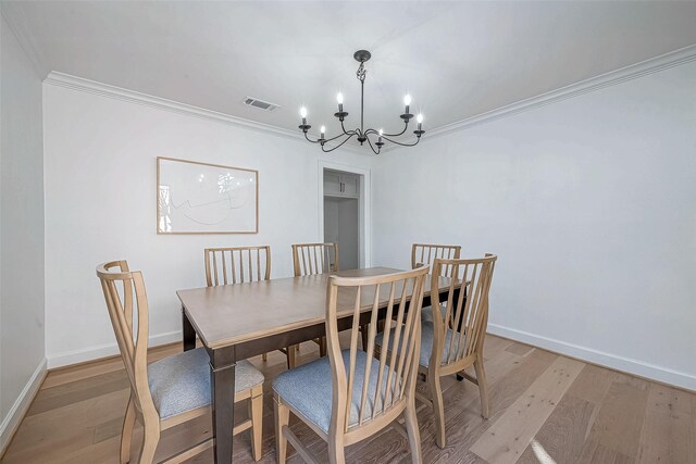 dining area featuring crown molding, light hardwood / wood-style flooring, and a chandelier