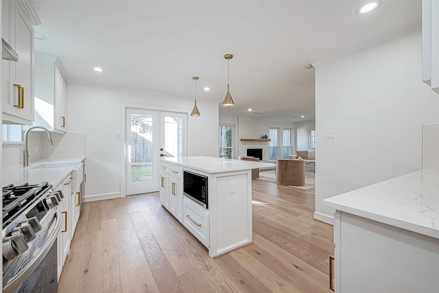 kitchen with stainless steel stove, white cabinetry, built in microwave, and light hardwood / wood-style flooring