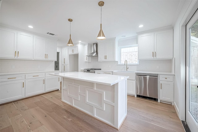 kitchen featuring white cabinets, wall chimney range hood, stainless steel appliances, and a wealth of natural light