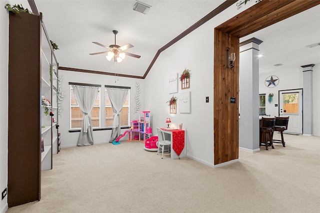 playroom with light carpet, vaulted ceiling, ceiling fan, ornamental molding, and decorative columns