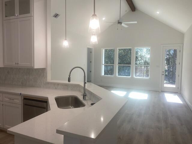 kitchen featuring pendant lighting, dishwasher, sink, ceiling fan, and an island with sink