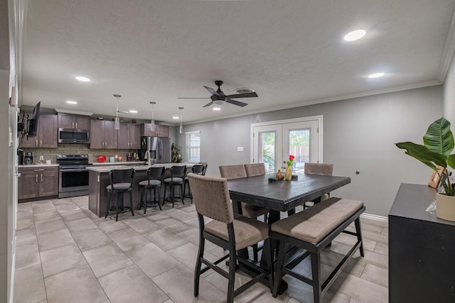 tiled dining space with ceiling fan, sink, crown molding, and french doors