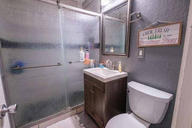 bathroom featuring vanity, toilet, and a shower with shower door