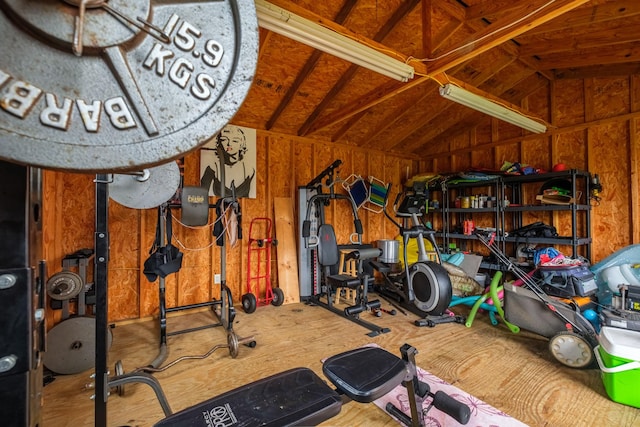 workout area with wood walls and lofted ceiling