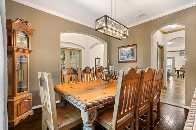 dining area featuring dark hardwood / wood-style flooring, ornamental molding, a wealth of natural light, and a chandelier