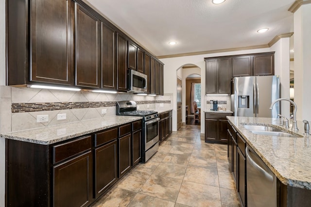 kitchen featuring sink, ornamental molding, appliances with stainless steel finishes, tasteful backsplash, and dark brown cabinetry