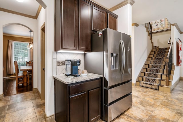 kitchen with stainless steel fridge, ornamental molding, tasteful backsplash, light stone counters, and dark brown cabinetry