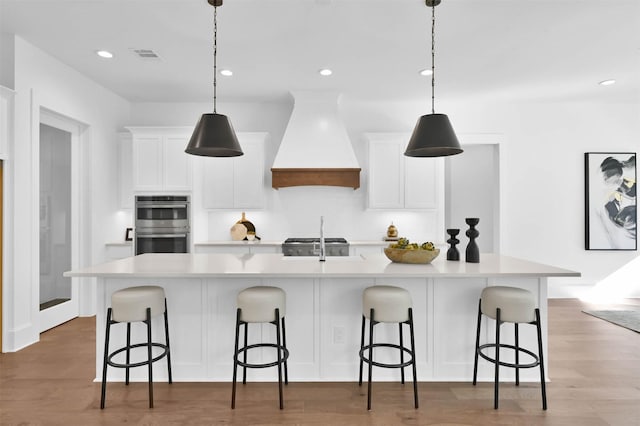 kitchen with sink, white cabinetry, a spacious island, and custom exhaust hood