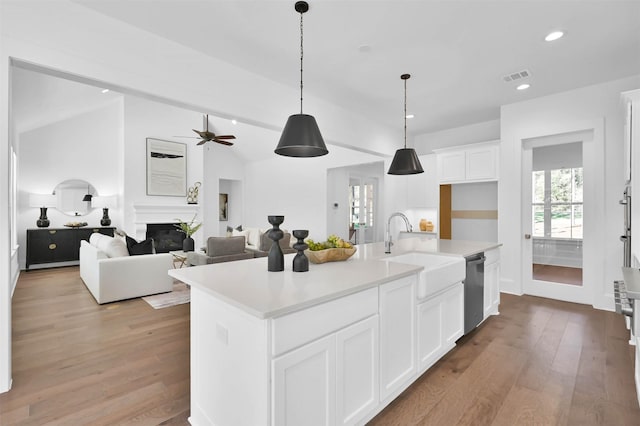 kitchen featuring sink, light hardwood / wood-style flooring, stainless steel dishwasher, a center island with sink, and white cabinets