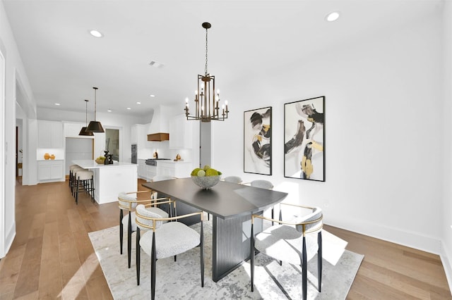 dining area with an inviting chandelier and light hardwood / wood-style flooring