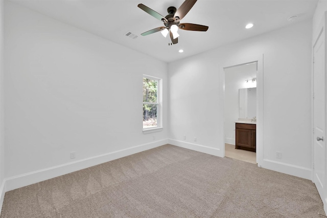 unfurnished bedroom with connected bathroom, light colored carpet, and ceiling fan