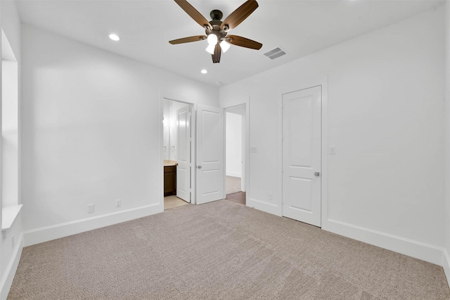 unfurnished bedroom featuring ceiling fan, a closet, light colored carpet, and ensuite bath