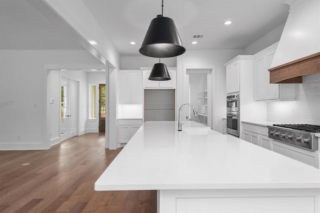 kitchen featuring hardwood / wood-style floors, custom exhaust hood, a spacious island, sink, and white cabinetry