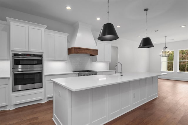 kitchen with a center island with sink, appliances with stainless steel finishes, and custom exhaust hood