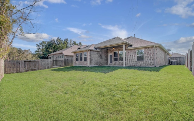 rear view of property with ceiling fan, a yard, and central AC