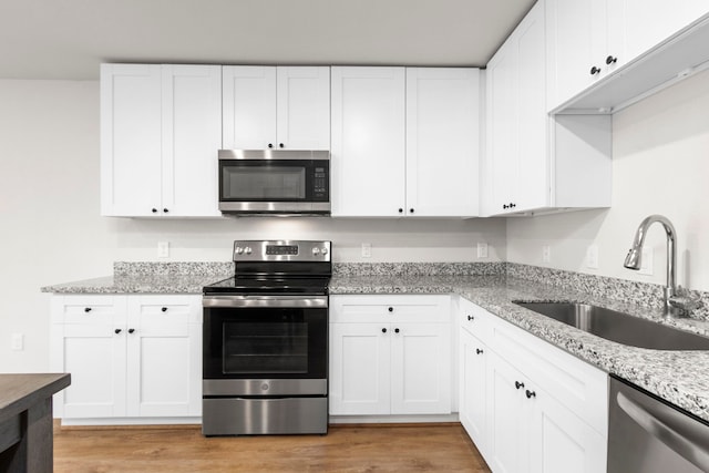 kitchen with sink, white cabinets, light hardwood / wood-style floors, and appliances with stainless steel finishes