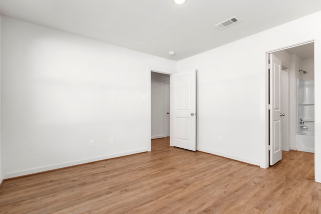 unfurnished bedroom with ensuite bathroom and light hardwood / wood-style floors