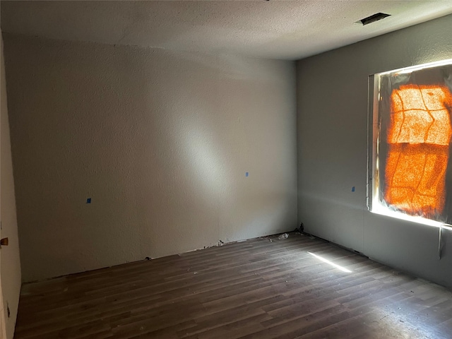 unfurnished room with dark hardwood / wood-style floors and a textured ceiling