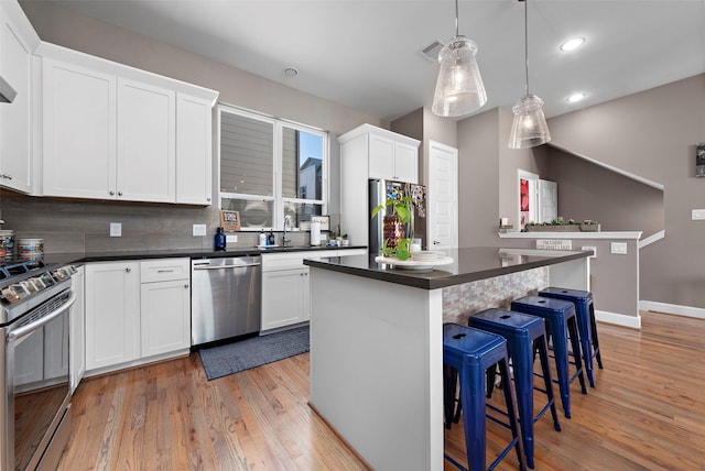 kitchen featuring white cabinetry, sink, a center island, stainless steel appliances, and light hardwood / wood-style floors