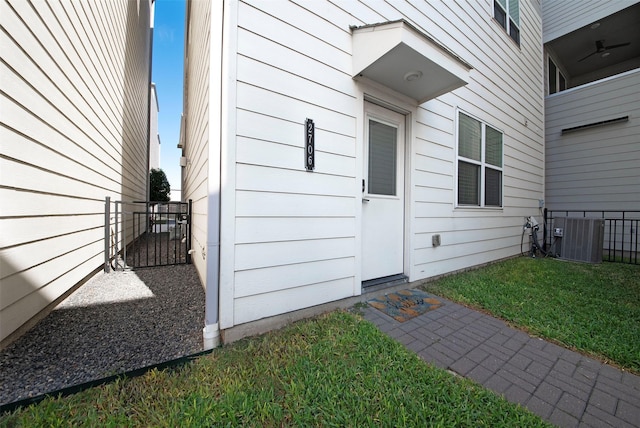 doorway to property with central air condition unit and a yard