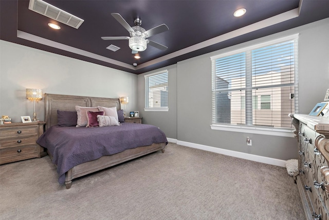 carpeted bedroom with a tray ceiling and ceiling fan