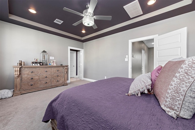 bedroom featuring ceiling fan, light carpet, and a tray ceiling