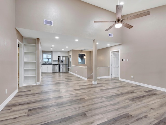24 N Omega St, La Marque, TX 77568 - unfurnished living room featuring ceiling fan, a high ceiling, and light hardwood / wood-style flooring