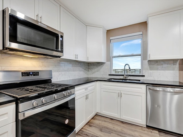 24 N Omega St, La Marque, TX 77568 - kitchen with sink, stainless steel appliances, light hardwood / wood-style floors, decorative backsplash, and white cabinets