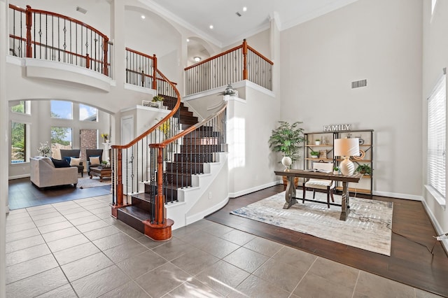 entryway with hardwood / wood-style floors, a towering ceiling, crown molding, and a wealth of natural light