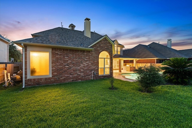 back house at dusk with a lawn